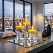 Yellow floating candles in glass cylinders on a square mirror with a skyline - thumbnail number 5