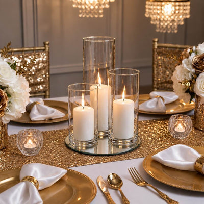 Lit pillar candles in glass cylinders on a gold-sequined table setting - thumbnail number 3