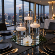 Lit floating candles in glass cylinders on a mirror tray on a dinner table with a city view - thumbnail number 6