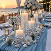 Lit white candles in glass vases filled with silver faux diamond gems on a blue beach table runner - thumbnail number 4