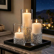 Lit white candles in glass vases filled with silver faux diamond gems on a black decorative tray - thumbnail number 7
