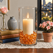 A tall glass cylinder vase with a lit candle surrounded by orange acrylic ice beads on a table - thumbnail number 7