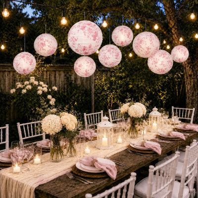 Pink floral French toile paper lanterns lit over an outdoor dining table - thumbnail number 7