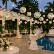 Green floral paper lanterns hang over an outdoor patio party near a pool - thumbnail number 6