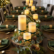 Assorted glowing flameless LED pillar candles on green-themed table with wooden tray - thumbnail number 4