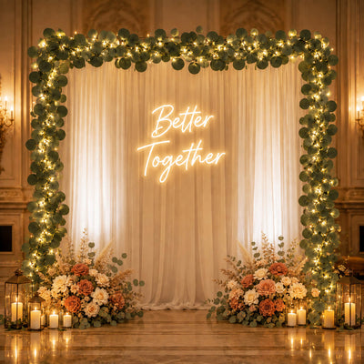 Eucalyptus garland lights frame a wedding backdrop with "Better Together" neon sign - thumbnail number 5