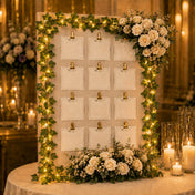 Ivy garland string lights framing a wedding seating chart board decorated with white roses - thumbnail number 7