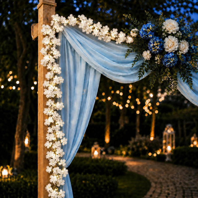 Cherry blossom garland string lights decorating a wooden wedding arbor with blue drapes - thumbnail number 3