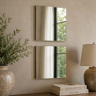 Two square mirrors mounted vertically on a light wall above a table with books and a lamp - thumbnail number 6