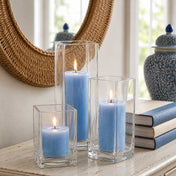 Three lit light blue candle and square holder sets arranged on a console table near a mirror - thumbnail number 6