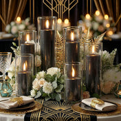 Lit black pillar candles in glass cylinders arranged with white roses and gold ferns on a table - thumbnail number 5