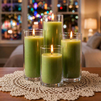 Four green pillar candles in glass vases on a crocheted doily with blurred holiday lights - thumbnail number 6