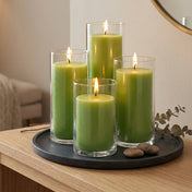 Four green pillar candles in glass cylinders on a black tray with smooth stones - thumbnail number 6