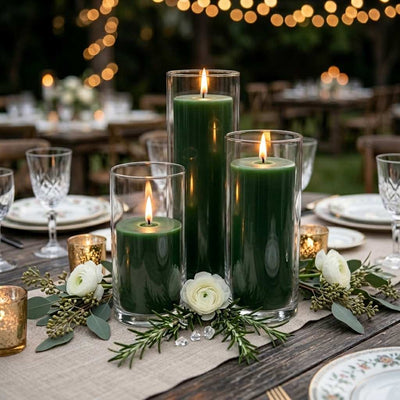 Three lit dark green candles in glass cylinders on a table with white flowers and greenery - thumbnail number 6