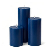 Three unlit navy blue pillar candles in assorted sizes on a solid white background - thumbnail number 1