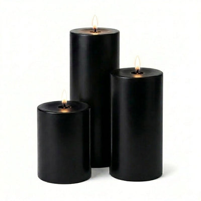 Three lit black pillar candles in assorted heights on a white background - thumbnail number 2