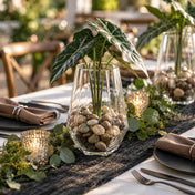 Faceted glass vase filled with polished natural stones and green leaves on a table - thumbnail number 5