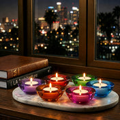 Glowing glass tealight holders on marble tray beside books and city lights - thumbnail number 13