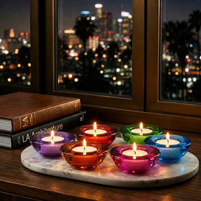 Glowing glass tealight holders on marble tray beside books and city lights - thumbnail number 13