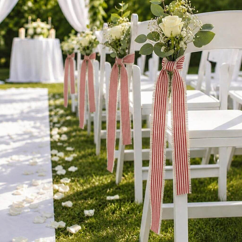 Red and white striped linen ribbons tying small floral bouquets to outdoor white wedding chairs - thumbnail number 2