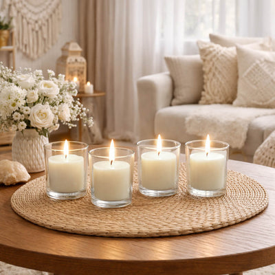 Four lit white candles in glass votives on a woven mat in a cozy living room - thumbnail number 6