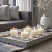 Lit white candles in glass votives on a concrete tray in a living room - thumbnail number 7