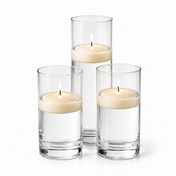 Trio of ivory floating candles burning in glass cylinder holders - thumbnail number 1