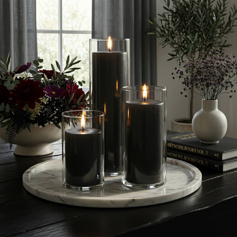 Lit pillar candles in glass holders on a marble tray surrounded by floral decor - thumbnail number 4