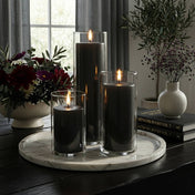 Lit pillar candles in glass holders on a marble tray surrounded by floral decor - thumbnail number 3