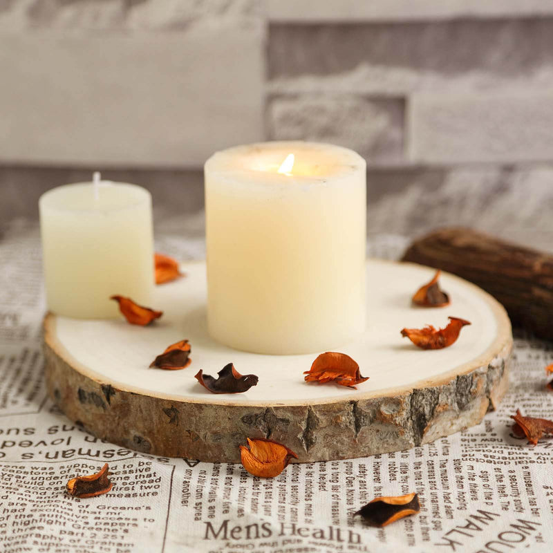 Candle on a wooden slice with dried petals on newspaper background. - thumbnail number 1
