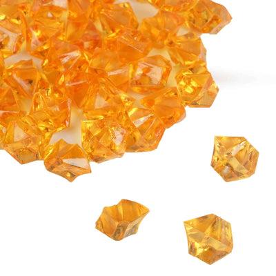 Scattered orange acrylic vase filler crystals on white background - thumbnail number 1