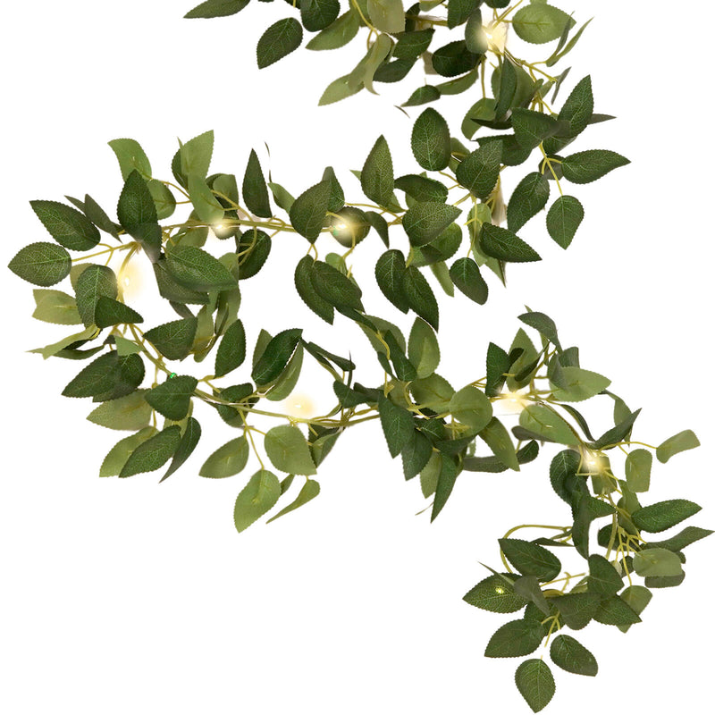 Vibrant greenery garland with warm string lights on white background - thumbnail number 1
